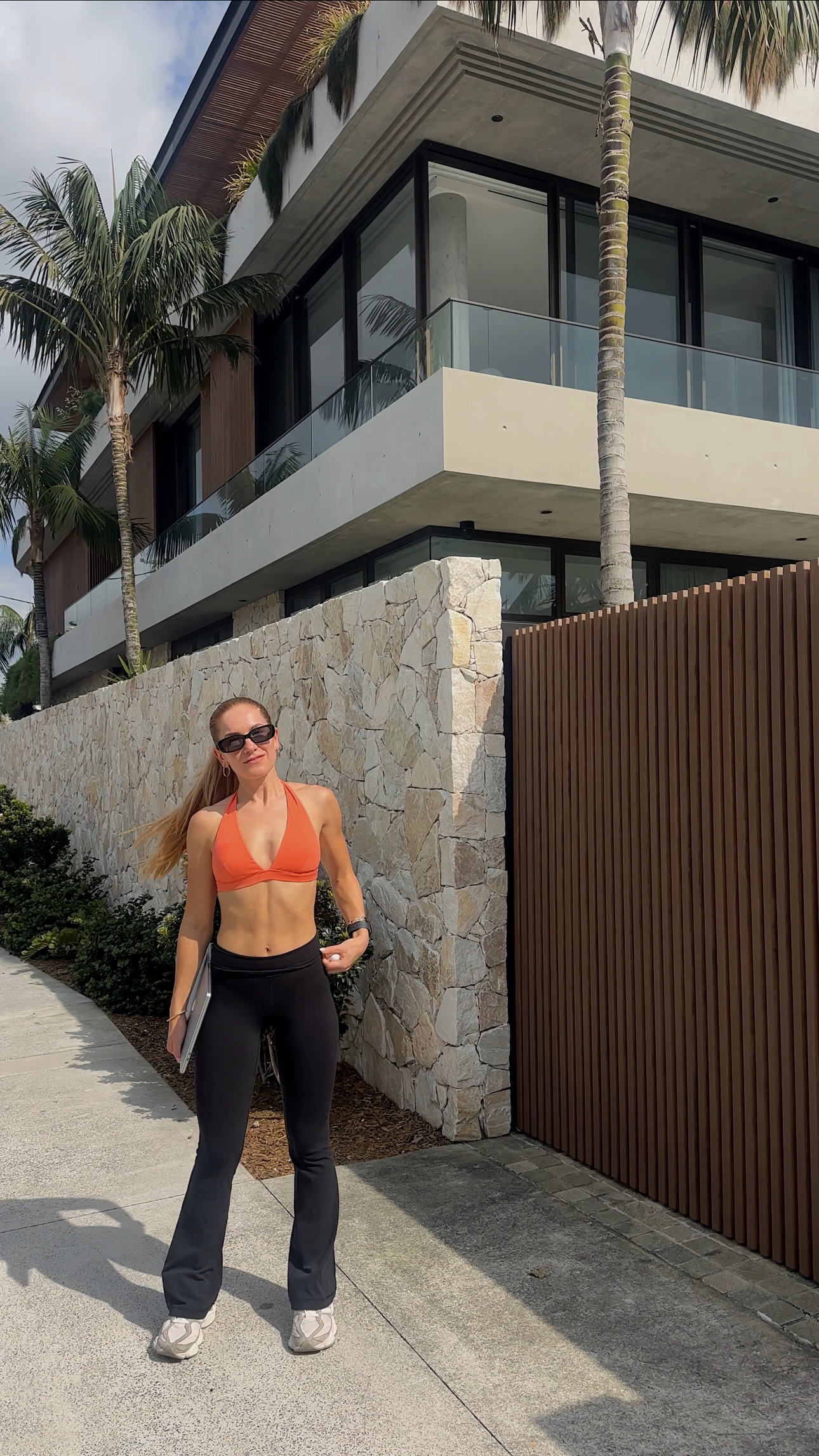 Cat Martin – Your Daily Habits Create Your Reality – fitness lifestyle photo in orange crop top and black Lululemon leggings